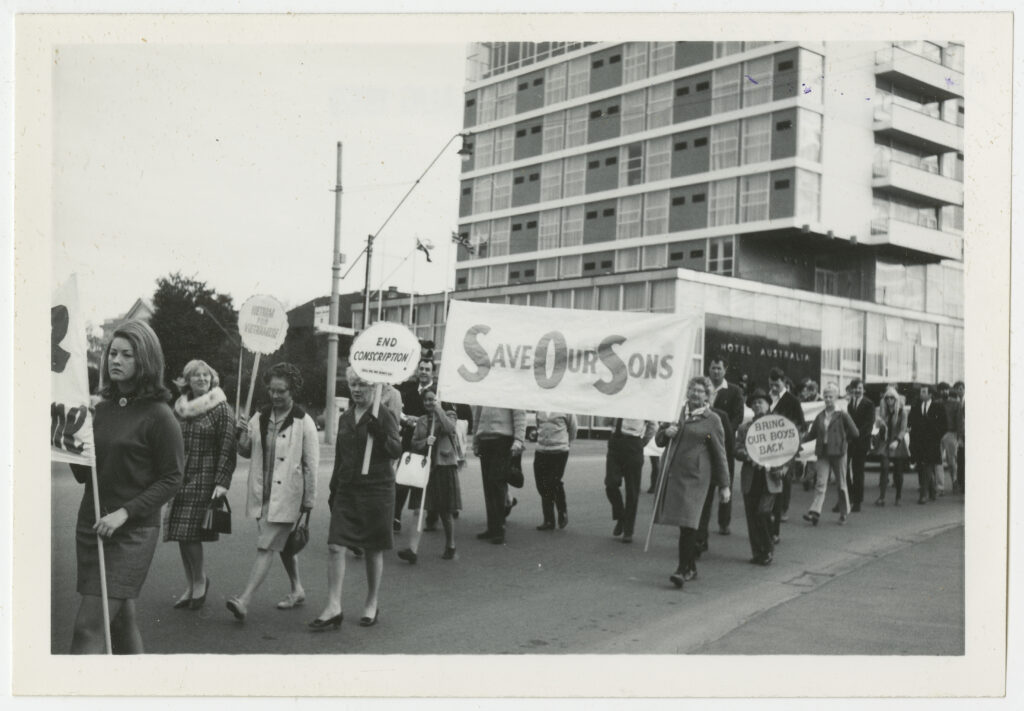 International Women’s Day. Women protest conscription and war on World Peace Day March near the Hotel Australia, King William Street, North Adelaide, 1969. Banners reading, "End Conscription", "Save our Sons", and "Bring our boys back". Part of the Anti-Vietnam War and Anti-conscription movements in Australia. [By Hal Pritchard via Wikimedia Commons]